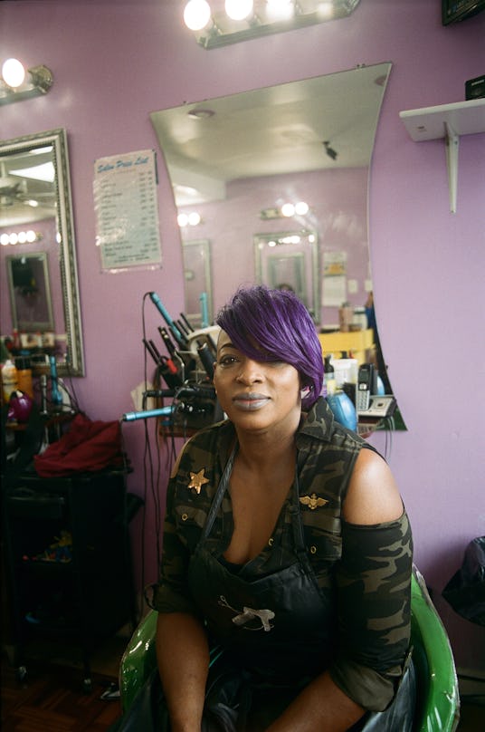 A woman at the salon posing with purple hair parted to the side 