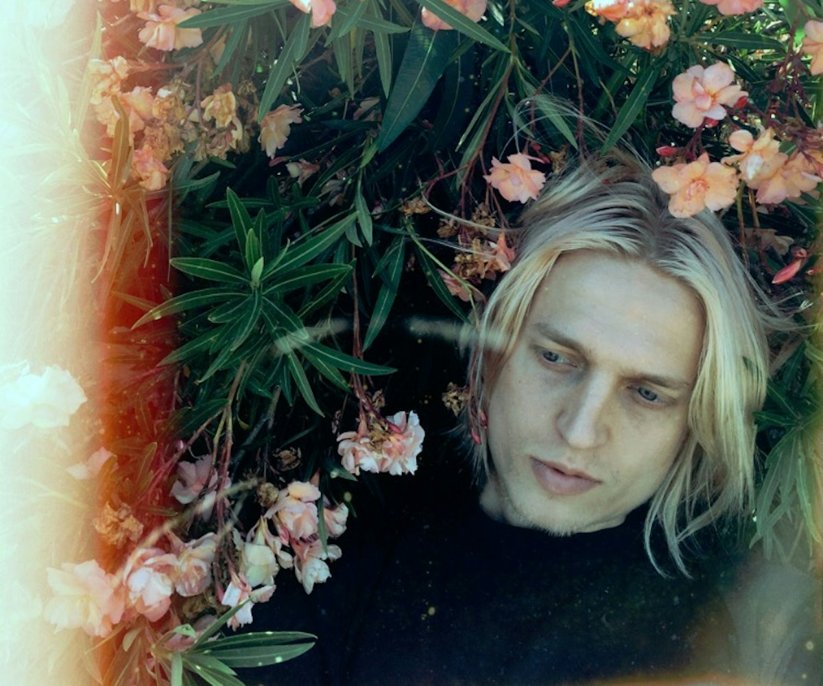 Artist Mosss posing in a field of flowers for a cover of  “Here If You Want (Pale Blue).”