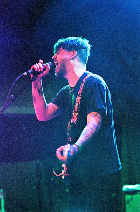 Nathan Williams of the Wavves band performing on stage singing into a microphone and holding a guita...