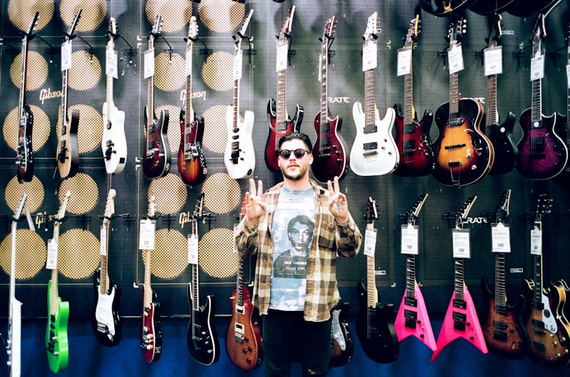 Nathan Williams of the Wavves band in sunglasses, standing in front of the wall full of electric gui...