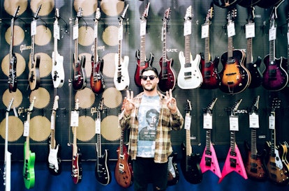 Nathan Williams of the Wavves band in sunglasses, standing in front of the wall full of electric gui...