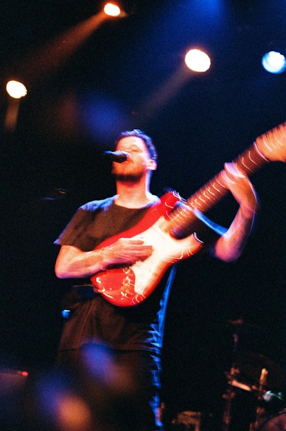 Nathan Williams of the Wavves band in motion, playing a guitar and singing; slightly blurred