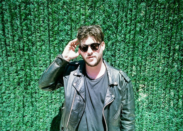 Nathan Williams of the Wavves band wearing a black leather jacket with sunglasses against a grassy g...