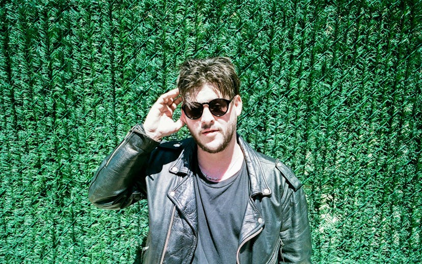 Nathan Williams of the Wavves band wearing a black leather jacket with sunglasses against a grassy g...