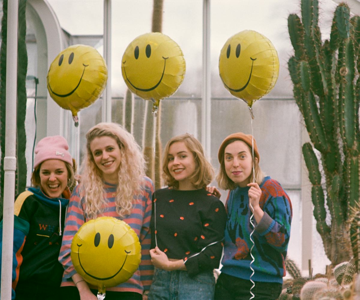 Members of Chastity Belt posing with yellow smiley balloons 