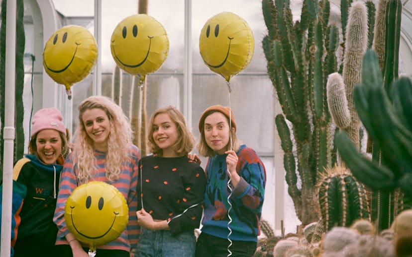 Members of Chastity Belt posing with yellow smiley balloons