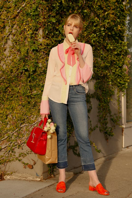 Lucy Boynton in a white shirt and pink coat licking an ice cream in a scene from Sing Street