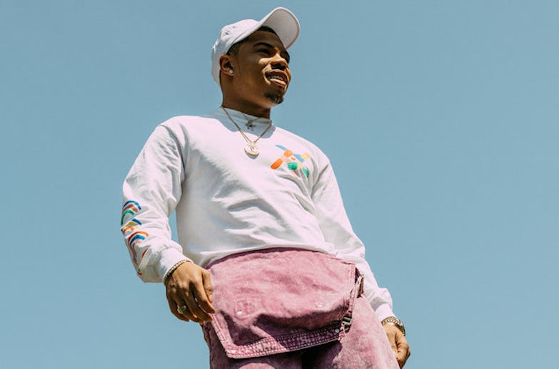 Taylor Bennett wearing a white cap in combination with a white hoodie and purple jeans 