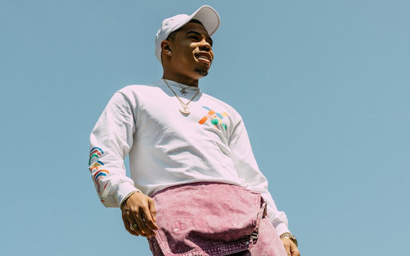 Taylor Bennett wearing a white cap in combination with a white hoodie and purple jeans 