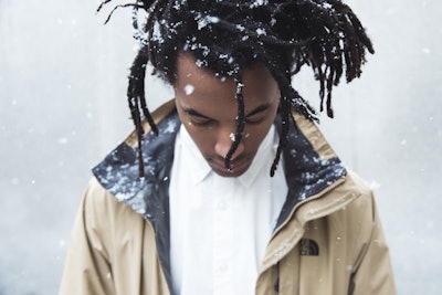 Conner Youngblood with dreadlock hairstyle with snowflakes in his hair in a white shirt and beige ja...