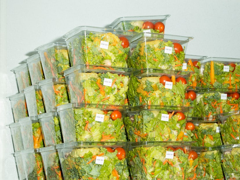 A lot of plastic boxes filled with various fresh vegetable salads stacked