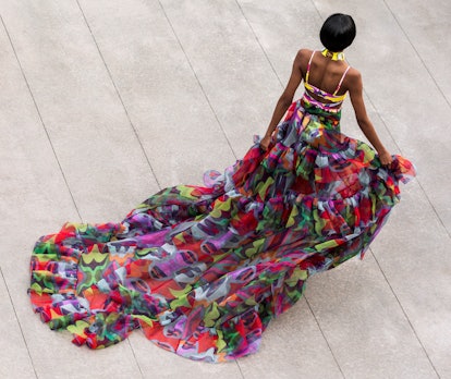 Model in a long multicolored dress walking down the runway 