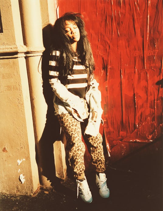 SZA leaning on a wall with her eyes shut. She's wearing a striped sweater and his taking off her bro...