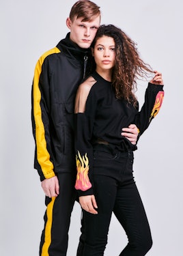 A male model dressed in the anorak track pullover in black and yellow posing next to a female model ...