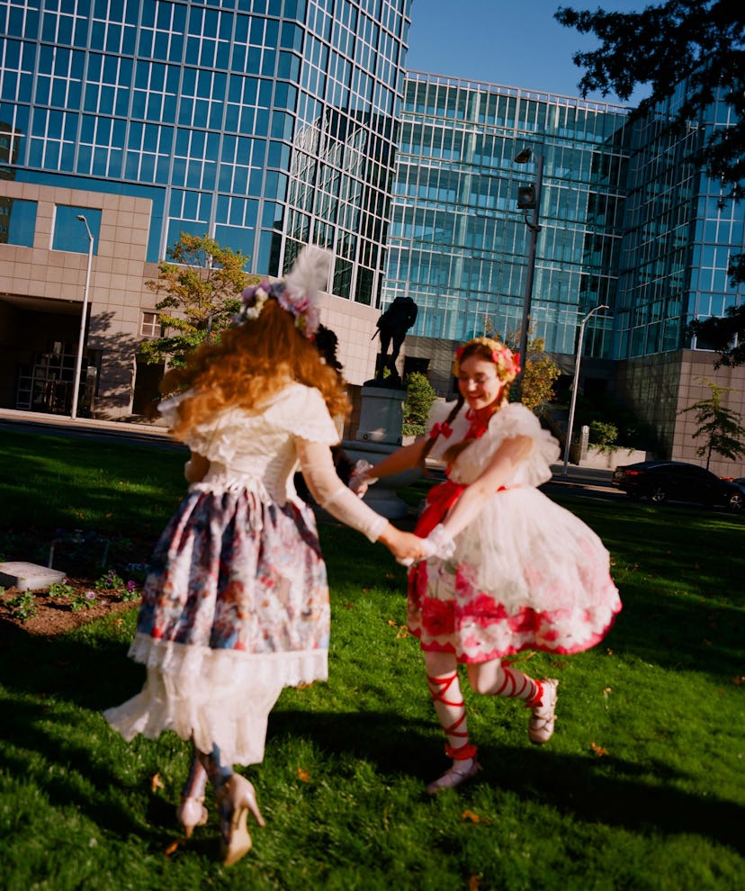 Two girls dancing on the grass while wearing bell-shaped skirts and flowers in their hair  