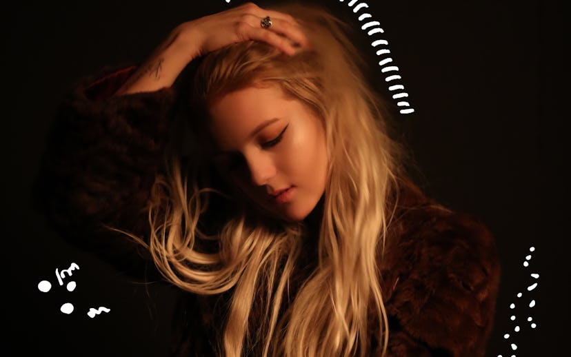 Wrenn sitting in the dark wearing a brown outfit with her hand on her head looking down while squigg...