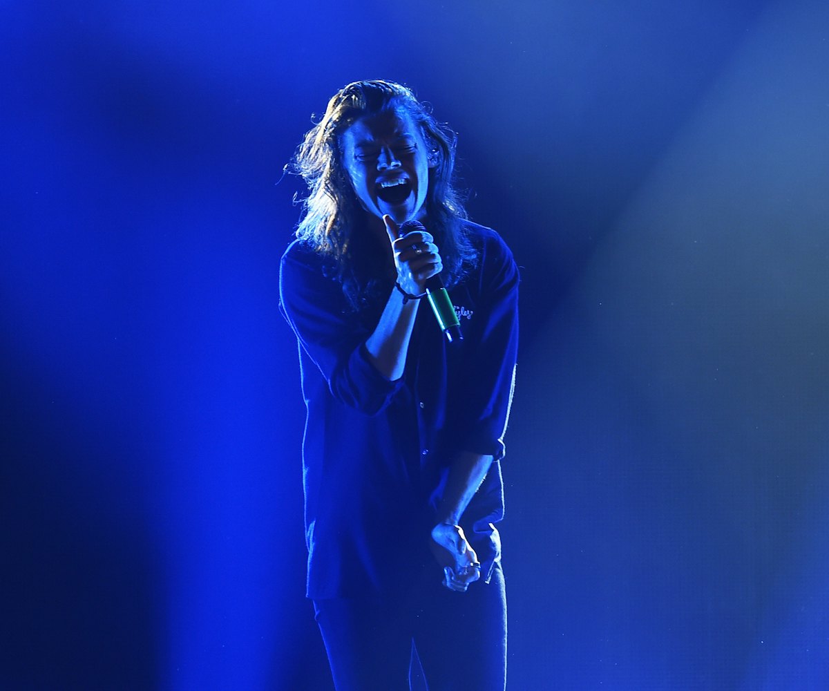 Harry Styles singing on stage under blue lights