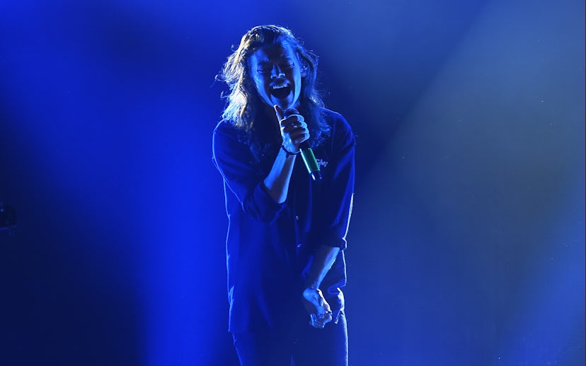 Harry Styles singing on stage under blue lights