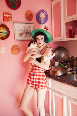 Stella Rose Saint Clair in her pink kitchen holding a cat