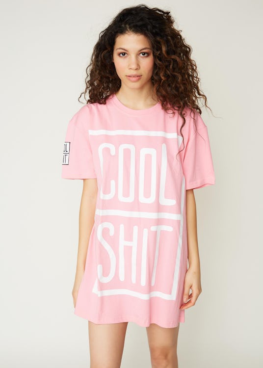 A brunette woman posing in a pink cool shit tee