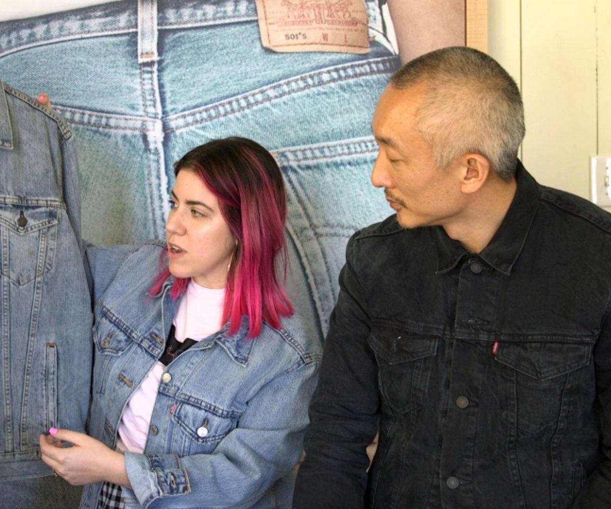 Woman with a brown/pink bob-length haircut showing a denim Levi's jacket to Jonathan Cheung who's we...