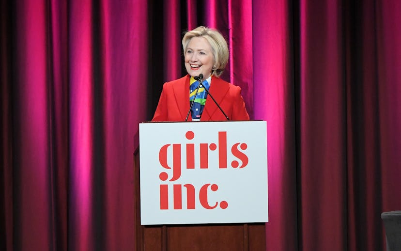 Hillary Clinton wearing a red suit giving a speech about her loss in the elections