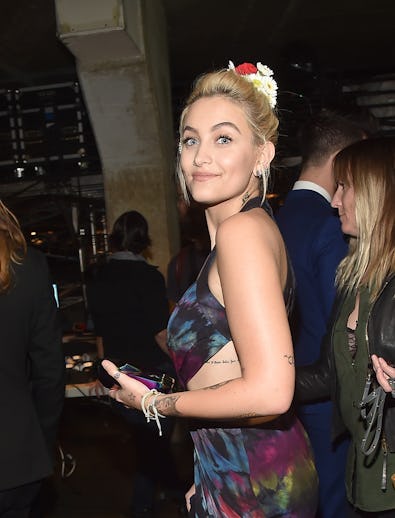 Paris Jackson smiling while wearing a blue dress and flowers in her hair