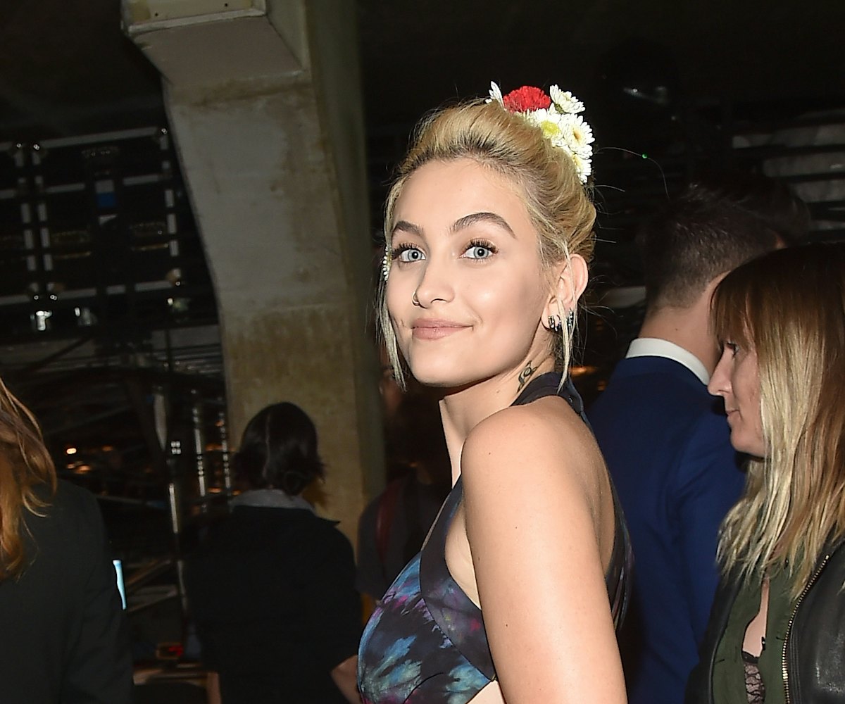 Paris Jackson is smiling at the photographer at the event while wearing a blue dress and flowers in ...