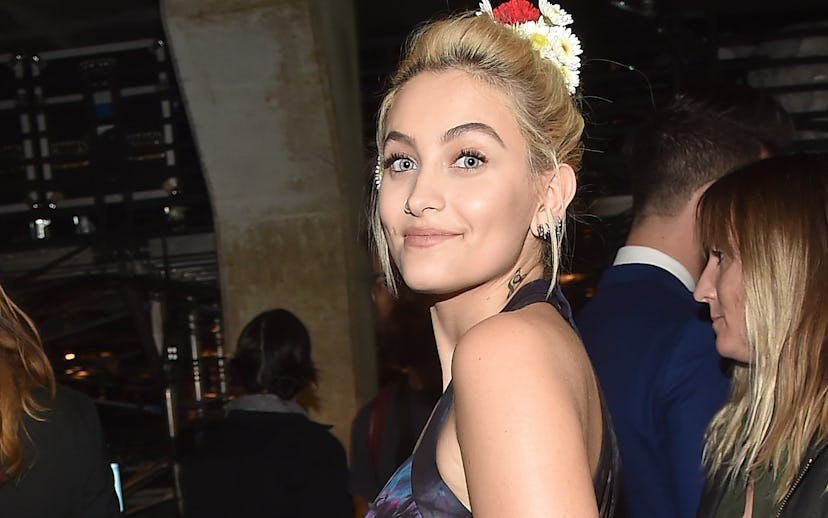 Paris Jackson smiling while wearing a blue dress and flowers in her hair