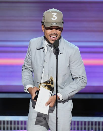 Chance the Rapper wearing a grey suit and a matching snapback at the Grammy’s while holding the awar...