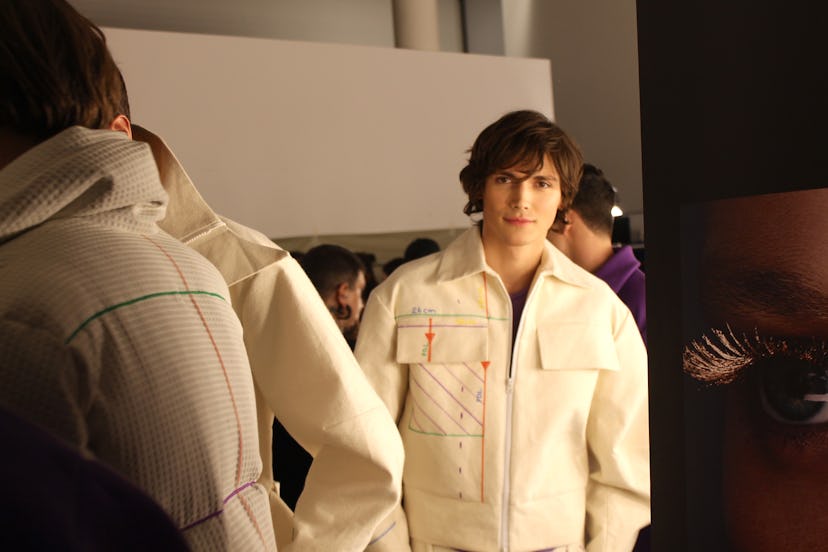 A male model posing in a white jacket at the Berlin Fashion Week