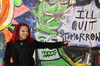 A red-haired woman posing next to a wall with "I'll quit tomorrow" text