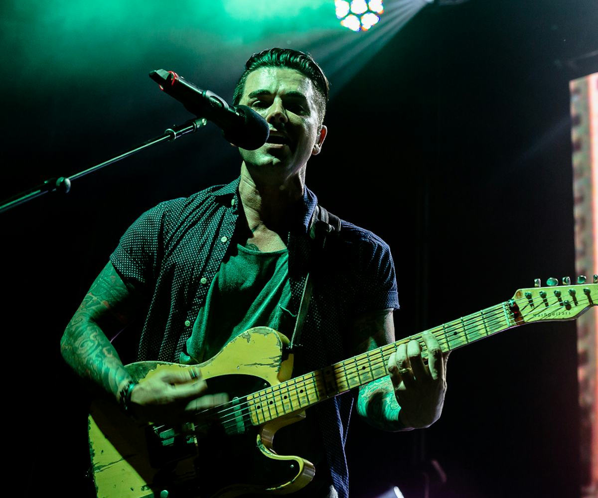 Chris Carrabba performing live on stage, with a green spotlight on him