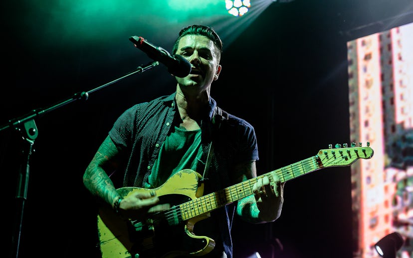Chris Carrabba performing live on stage, with a green spotlight on him