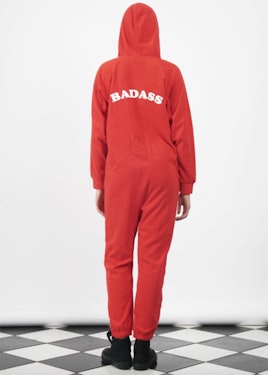 A model posing in a red onesie with a "badass" text sign on back