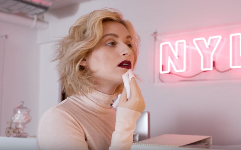 Gabrielle Korn standing in front of a mirror and taking off her lipstick