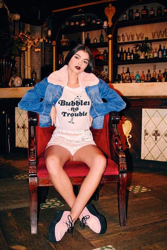Amy Douglas sitting while wearing a Fur Collared Denim Jacket, and pink velvet love shorts