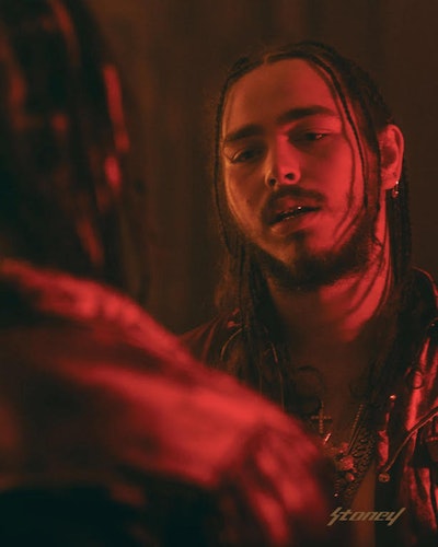 Post Malone looking at himself in the mirror with red lighting 