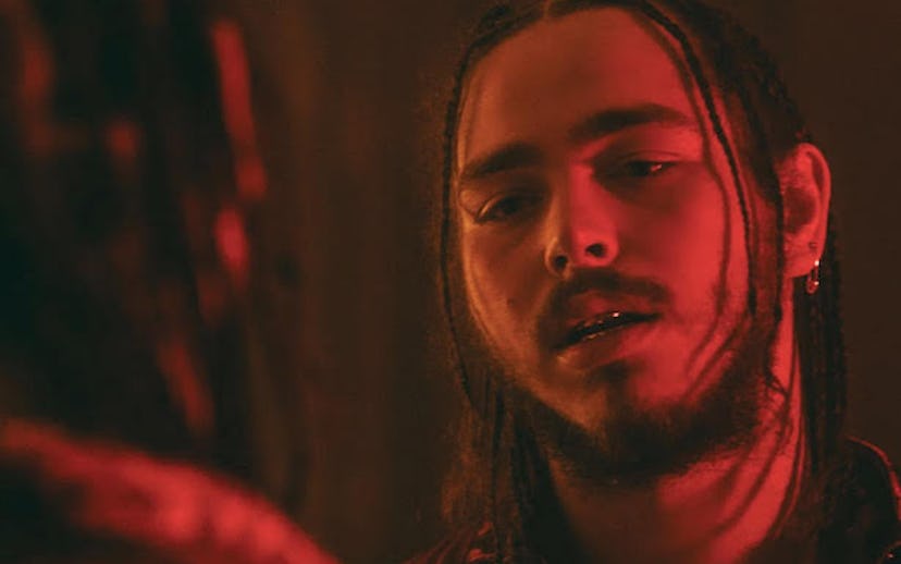 Post Malone looking at himself in the mirror with red lighting 