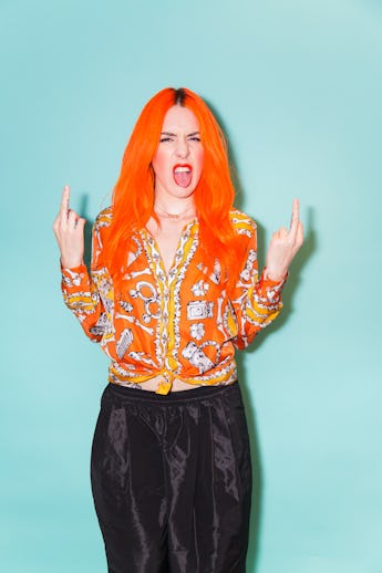 Kerin Rose Gold showing two middle fingers and sticking out her tongue in an orange shirt with a bon...