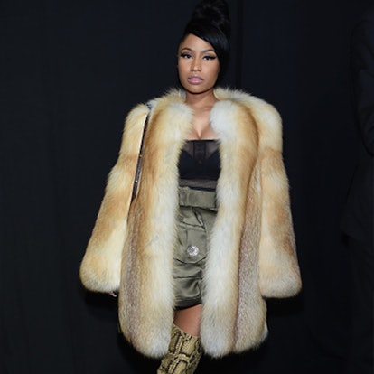 Nicki Minaj with short hair wearing a black top, olive skirt, and a beige fur coat