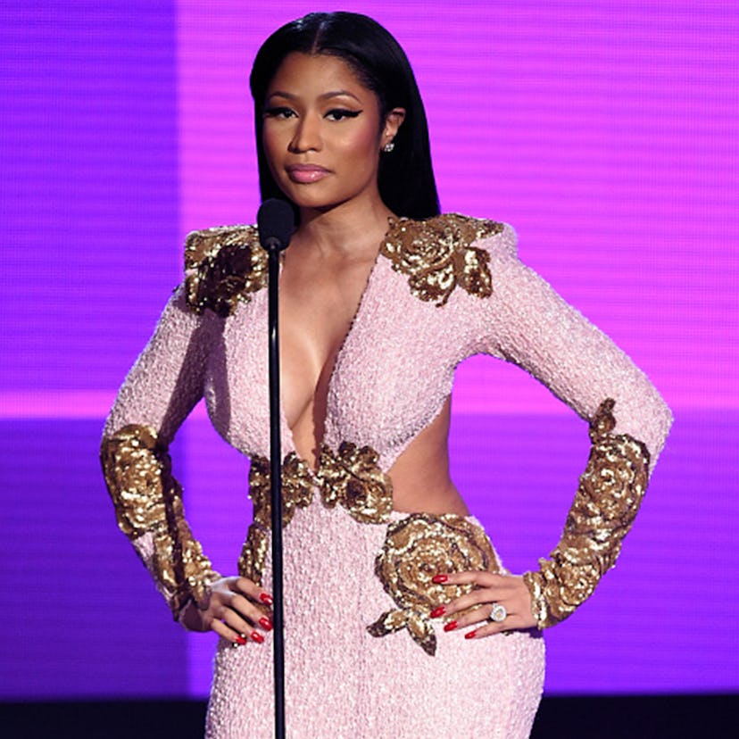 Nicki Minaj with straight hair and a black eyeliner wearing a cut out pink dress with gold details