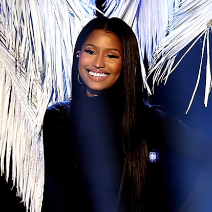 Nicki Minaj smiling to the camera while wearing a black suit