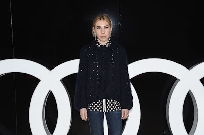 Zosia Mamet in a black sweater, a polka dot button-up and jeans 