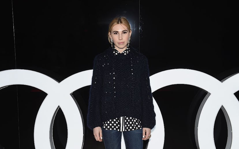 Zosia Mamet in a black sweater, a polka dot button-up and jeans 