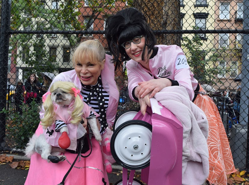 Two women dressed as characters from Grease with their dog in a matching outfit 