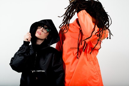 Two models wearing the Tastemaker Collective orange and black windbreaker jackets