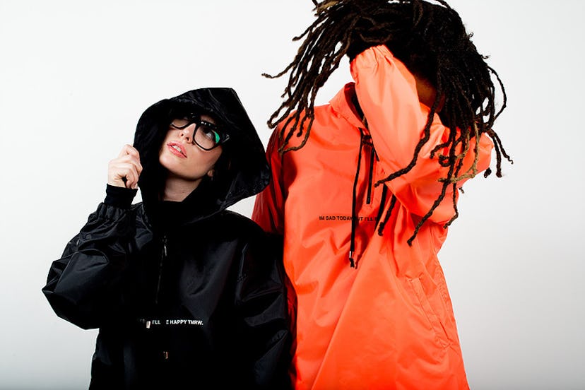 Two models wearing the Tastemaker Collective orange and black windbreaker jackets