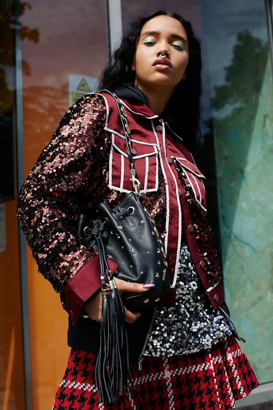 A model in a burgundy jacket with sequins with a red and white checkered skirt and a black coin buck...