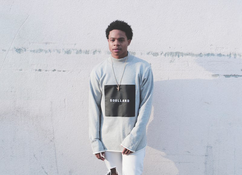 Chris Scholar wearing a grey hoodie with a black square in the middle with "SOULLAND" written inside...